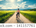 Woman riding mountain bike on dirt road and green wheat fields 141157761