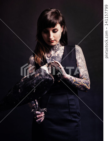 Fashion, woman and bird animal in studio for witchcraft or magic, mysterious and fantasy with punk culture. Person, eagle and isolated on black background for darkness and creepy grunge look. Fashion, woman and bird animal in studio for witchcraft or magic, mysterious and fantasy with punk culture. Person, eagle and isolated on black background for darkness and creepy grunge look. 141157799