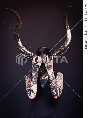 Horns, demon and woman with tattoo in studio for dark magic, horror or artistic aesthetic with mask. Creative nightmare, halloween culture or unique female person with scary bones on black background Horns, demon and woman with tattoo in studio for dark magic, horror or artistic aesthetic with mask. Creative nightmare, halloween culture or unique female person with scary bones on black background 141158279