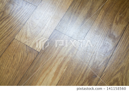 A close-up, overhead view shows a wooden floor with a diagonal pattern of planks. 141158560