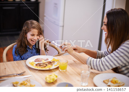 Mom, child and laugh in morning with breakfast for routine with quality time, happiness and nutrition. Mother, girl and together for bonding with food, feeding and homemade with love for healthy diet Mom, child and laugh in morning with breakfast for routine with quality time, happiness and nutrition. Mother, girl and together for bonding with food, feeding and homemade with love for healthy diet 141158657