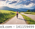 Woman riding mountain bike on asphalt bicycle path in countrysid 141159499