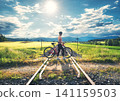 Female cyclist riding mountain bike and rural railroad at sunset 141159503