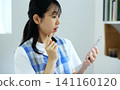 A woman in an apron looks at her smartphone in surprise. 141160120