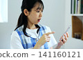 A woman in an apron looks at her smartphone in surprise. 141160121