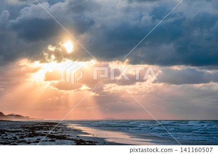 Beautiful sunset over the beach with dramatic clouds and shimmering ocean waves Beautiful sunset over the beach with dramatic clouds and shimmering ocean waves 141160507