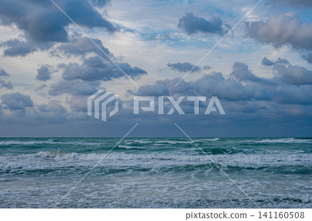 Waves crash on the shore under a cloudy sky at twilight on a beach Waves crash on the shore under a cloudy sky at twilight on a beach 141160508