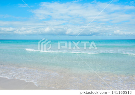 Calm ocean waves gently lap on the sandy shore under a bright blue sky Calm ocean waves gently lap on the sandy shore under a bright blue sky 141160513