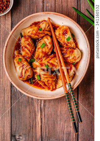 Delicious dumplings served in a bowl with a spicy sauce and green onions Delicious dumplings served in a bowl with a spicy sauce and green onions 141160532