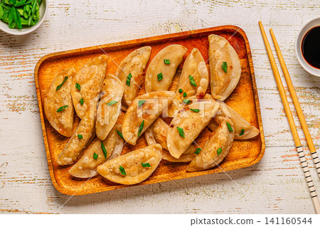 Dumplings on a wooden plate with chopsticks and soy sauce Dumplings on a wooden plate with chopsticks and soy sauce 141160544