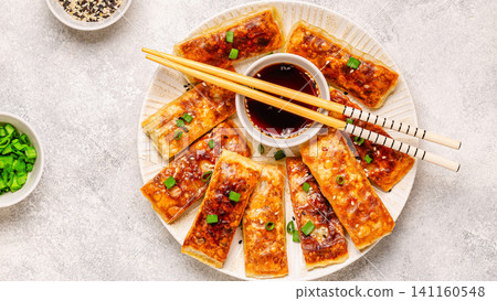 Dumplings are arranged on a plate with a small bowl of dipping sauce Dumplings are arranged on a plate with a small bowl of dipping sauce 141160548