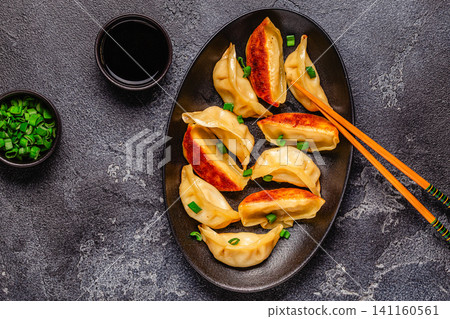 Dumplings are served on a black plate with green onion Dumplings are served on a black plate with green onion 141160561