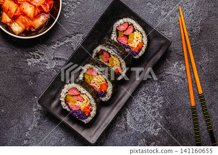 A black plate filled with kimbap (or gimbap) that have colorful fillings. A black plate filled with kimbap (or gimbap) that have colorful fillings. 141160655
