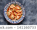 Wontons are placed in a bowl with spicy sauce. 141160733
