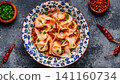Wontons are placed in a bowl with spicy sauce. 141160734