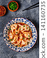 Wontons are placed in a bowl with spicy sauce. 141160735