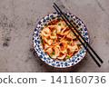Wontons are placed in a bowl with spicy sauce. 141160736
