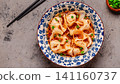 Wontons are placed in a bowl with spicy sauce. 141160737