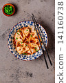 Wontons are placed in a bowl with spicy sauce. 141160738