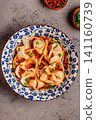 Wontons are placed in a bowl with spicy sauce. 141160739