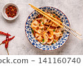 Wontons are placed in a bowl with spicy sauce. 141160740