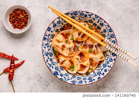Wontons are placed in a bowl with spicy sauce. 141160740