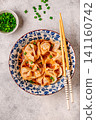 Wontons are placed in a bowl with spicy sauce. 141160742