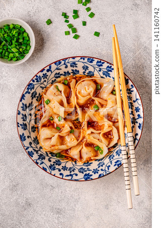 Wontons are placed in a bowl with spicy sauce. 141160742