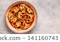 Wontons are placed in a bowl with spicy sauce. 141160743