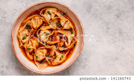 Wontons are placed in a bowl with spicy sauce. 141160743