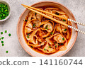 Wontons are placed in a bowl with spicy sauce. 141160744