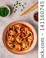 Wontons are placed in a bowl with spicy sauce. 141160745