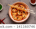 Wontons are placed in a bowl with spicy sauce. 141160746