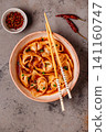 Wontons are placed in a bowl with spicy sauce. 141160747