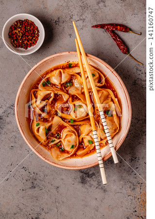 Wontons are placed in a bowl with spicy sauce. Wontons are placed in a bowl with spicy sauce. 141160747