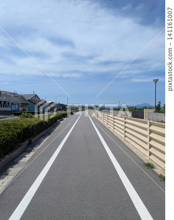A cycling path and walking trail stretch straight under the blue sky. A cycling path and walking trail stretch straight under the blue sky. 141161007