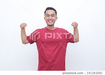 Young man smiles brightly, flexing arms. He wears a solid red t-shirt. His cheerful pose conveys confidence and energy. Ideal for fitness, wellness, or motivational themes Young man smiles brightly, flexing arms. He wears a solid red t-shirt. His cheerful pose conveys confidence and energy. Ideal for fitness, wellness, or motivational themes 141161081