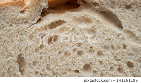 Full frame shot of the surface of sourdough bread. Sourdough is a type of bread leavened naturally using a fermented starte a mixture of flour and water rather than commercial yeast. Full frame shot of the surface of sourdough bread. Sourdough is a type of bread leavened naturally using a fermented starte a mixture of flour and water rather than commercial yeast. 141161199