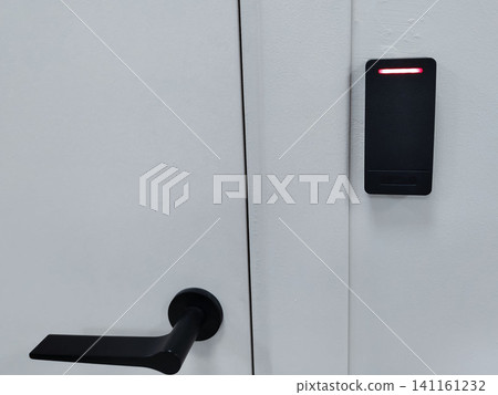 Modern door handle and electronic access control system mounted on a white wall, featuring a red indicator light for security access verification Modern door handle and electronic access control system mounted on a white wall, featuring a red indicator light for security access verification 141161232