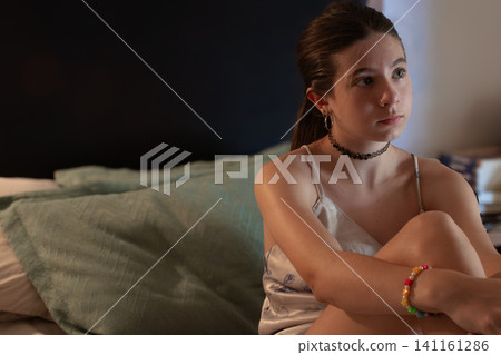 Teenager girl sitting on bed in dark room, thoughtfully observing something off-frame, capturing moments of solitude, contemplation, and the complexities of growing up Teenager girl sitting on bed in dark room, thoughtfully observing something off-frame, capturing moments of solitude, contemplation, and the complexities of growing up 141161286