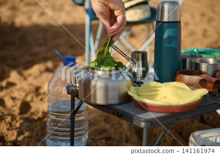 Outdoor camping breakfast with kettle, fresh herbs and pancakes on portable table Outdoor camping breakfast with kettle, fresh herbs and pancakes on portable table 141161974