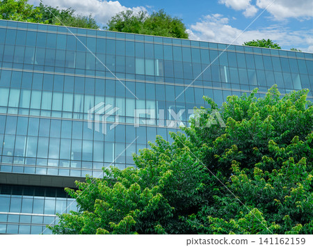 Eco-friendly building in modern city. Sustainable glass office building with trees for reducing carbon dioxide. Office building with green environment. Corporate building reduce CO2. Net zero emission Eco-friendly building in modern city. Sustainable glass office building with trees for reducing carbon dioxide. Office building with green environment. Corporate building reduce CO2. Net zero emission 141162159