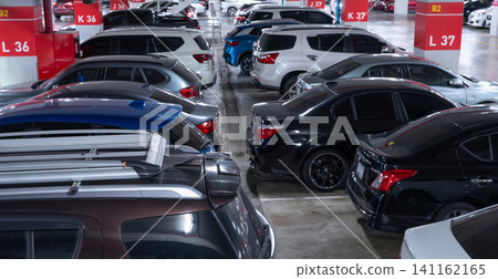 Busy underground car parking lot. Organized rows of vehicles in an urban hub. Urban convenience. Crowded parking space underground of the exhibition and convention center. Indoor car parking lot. 141162165