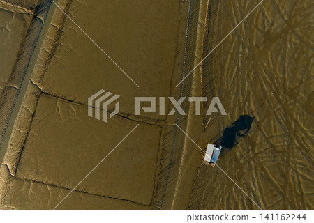 Aerial drone view of coastal mudflat. Natural blue carbon sink and carbon capture. Nature landscape. Coastal environment. Mud sea beach. Aquaculture farming. Shellfish farm. Eco-friendly conservation. Aerial drone view of coastal mudflat. Natural blue carbon sink and carbon capture. Nature landscape. Coastal environment. Mud sea beach. Aquaculture farming. Shellfish farm. Eco-friendly conservation. 141162244