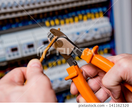 The man is repairing the switchboard voltage with automatic switches. The man is repairing the switchboard voltage with automatic switches. 141162320