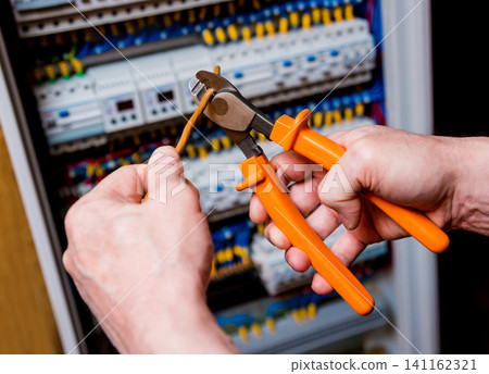 The man is repairing the switchboard voltage with automatic switches. The man is repairing the switchboard voltage with automatic switches. 141162321