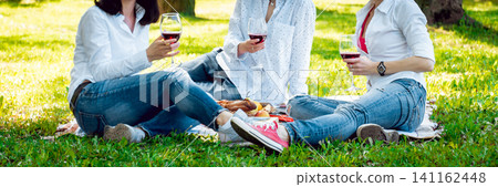 Young beautiful girls with glass of red wine in the park Young beautiful girls with glass of red wine in the park 141162448