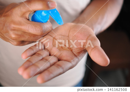 Hand applying hand sanitizer before entering a building Hand applying hand sanitizer before entering a building 141162508