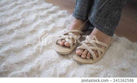 Feet in sandals on a soft rug indoors Feet in sandals on a soft rug indoors 141162586