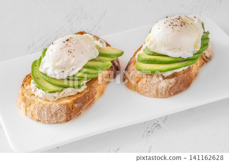 Avocado toast with poached eggs on artisan bread plate Avocado toast with poached eggs on artisan bread plate 141162628